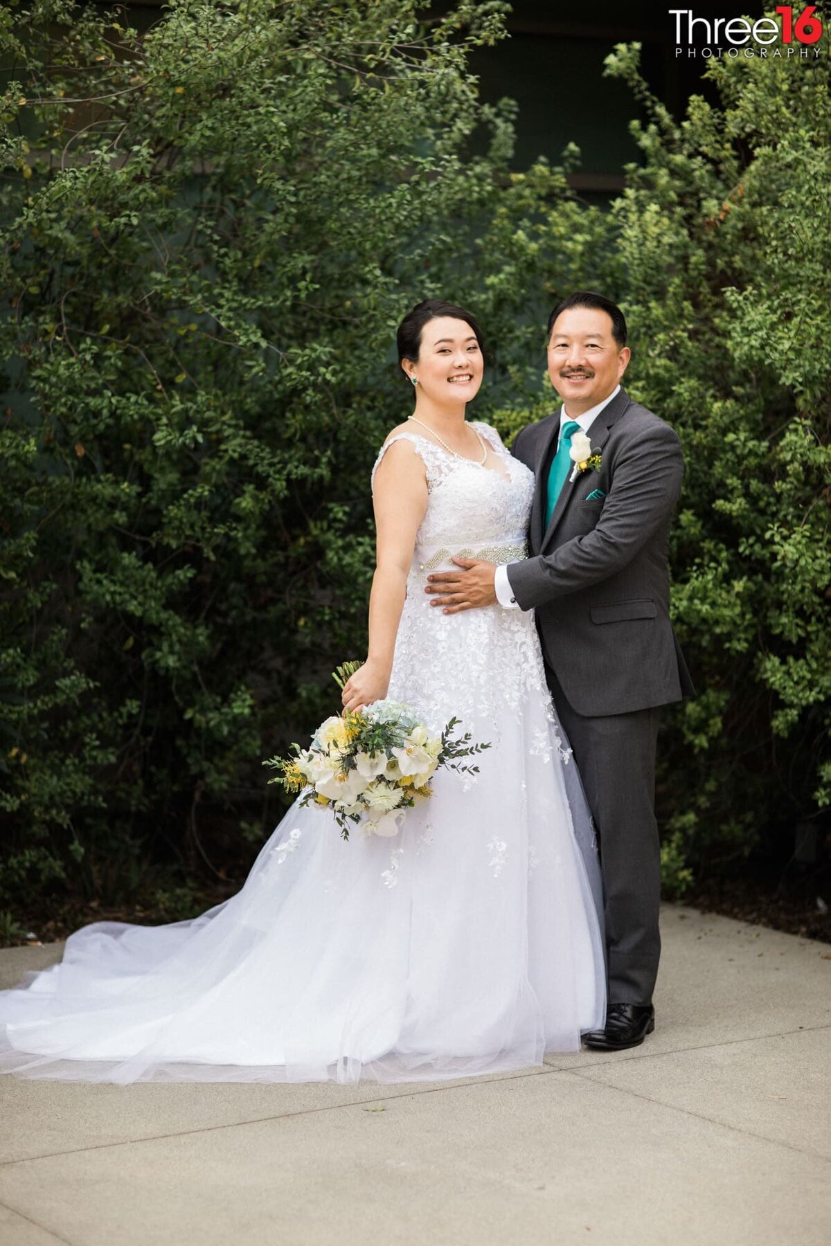 Groom holds his Bride's waist as they pose for photos