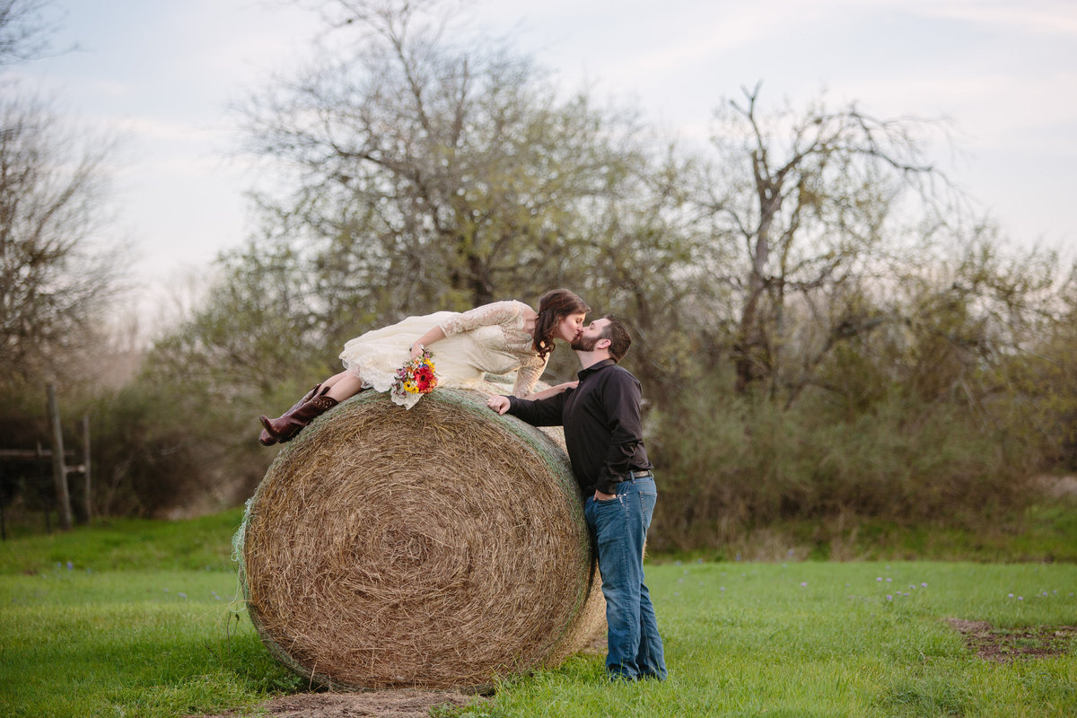 groom kissing his bride on a hay bale at Hoffman Ranch wedding venue