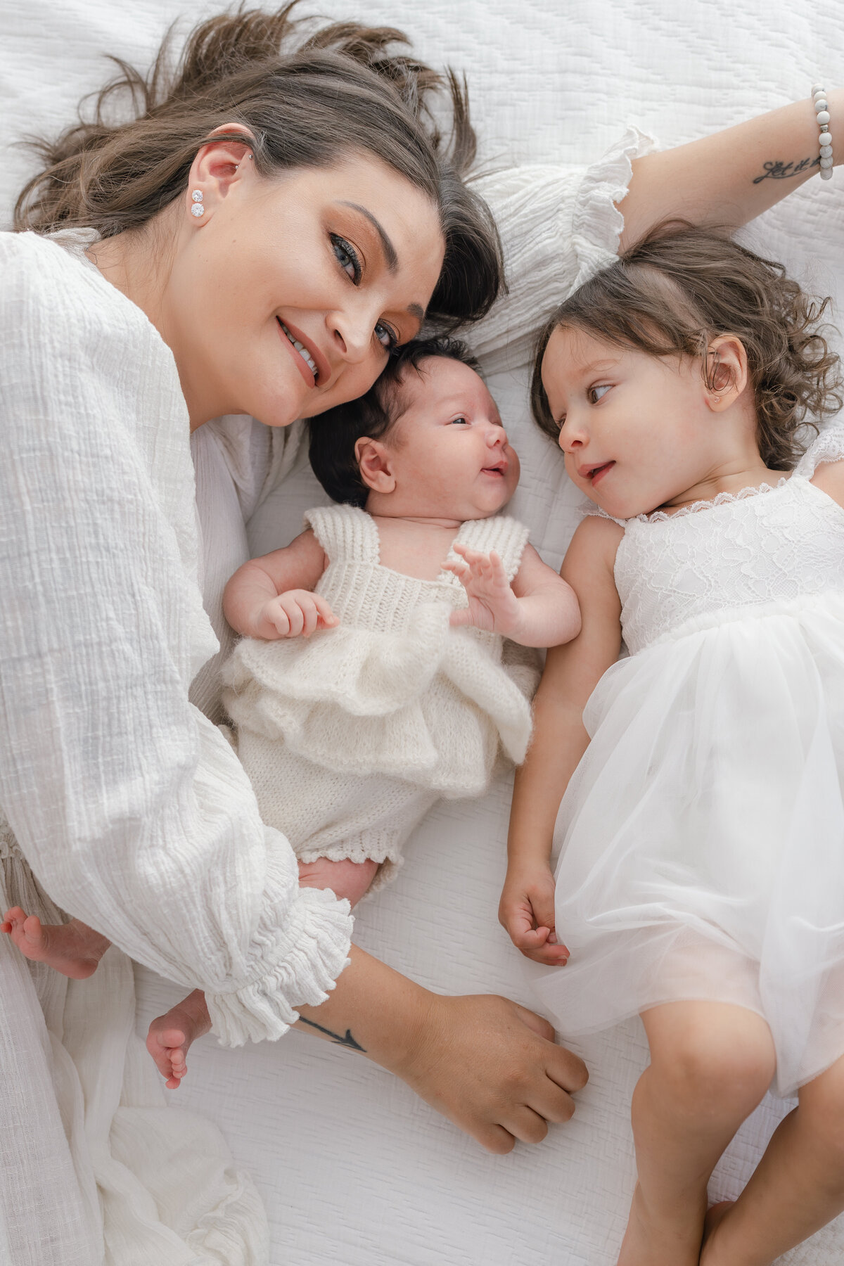 Mom cuddling baby and toddler during natural light Barrie newborn photography session 