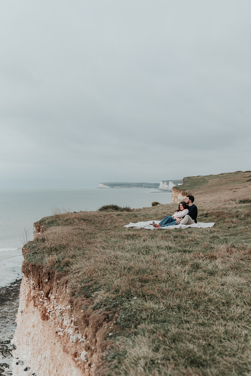 Couple relax on blanket by the cliffside at Beachy Head, Eastbourne