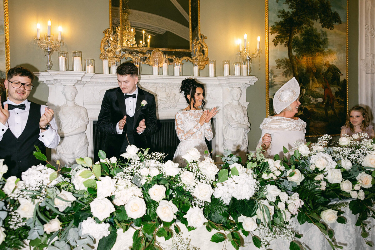 A wedding photo of the bride and groom clapping after a speech at their wedding at Luttrellstown Castle in Dublin Ireland