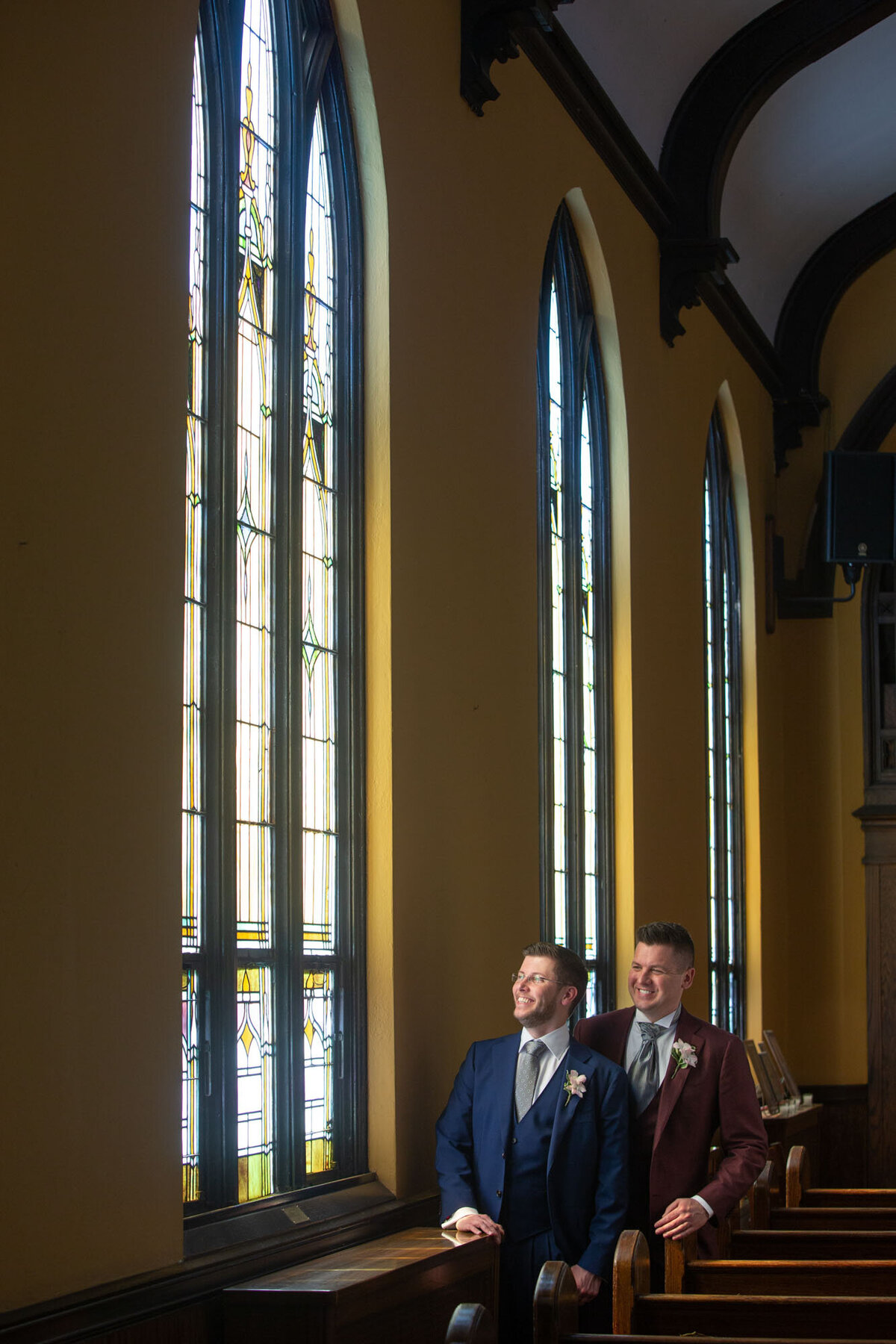 Two men standing in front of a stained glass window
