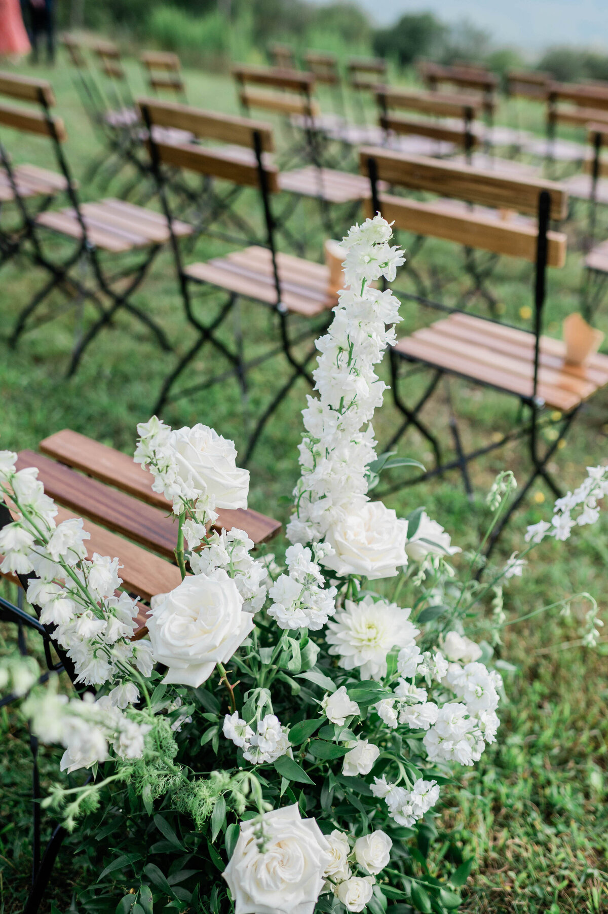 White florals beside wooden ceremony seats