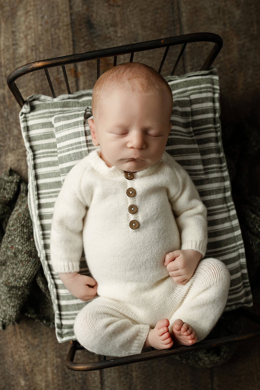 york pa newborn session baby boy laying on a striped tiny bed in a white knit romper