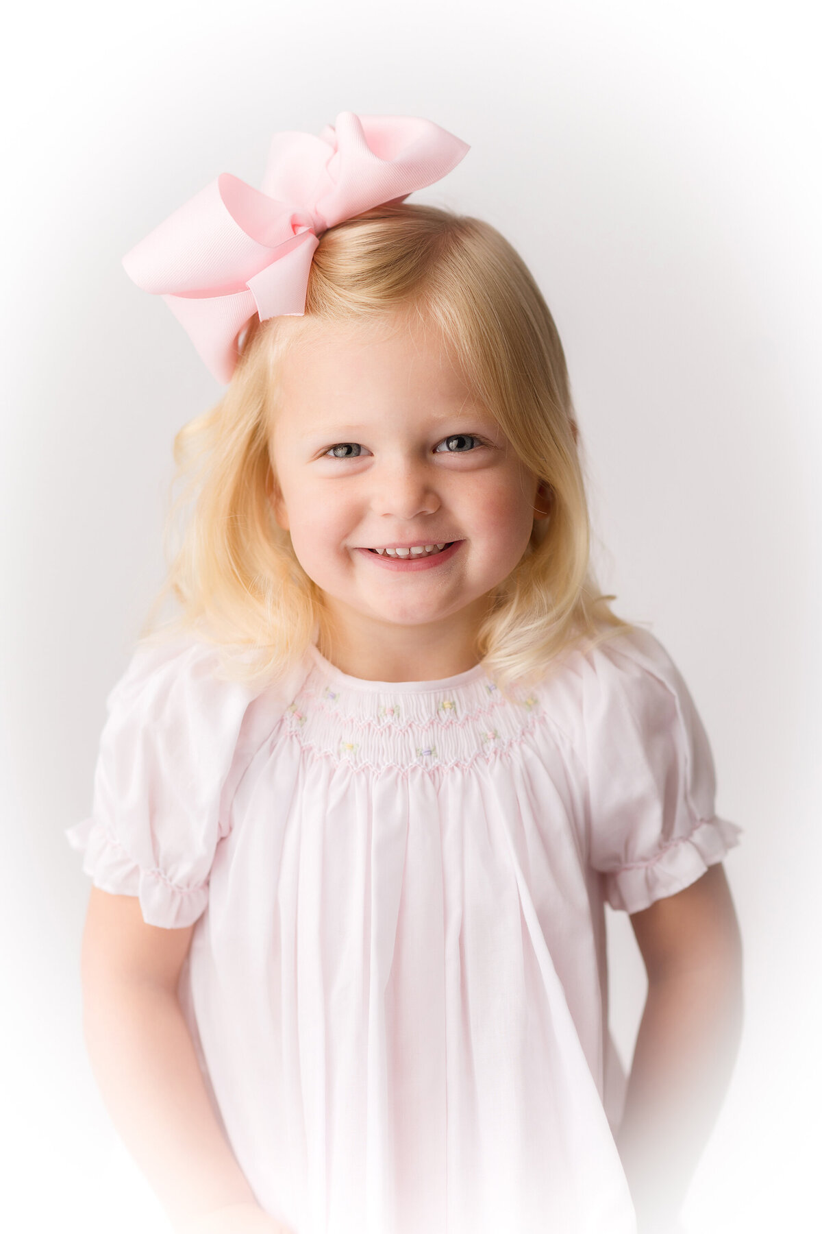 Little girls smiles at the camera during an Heirloom Portrait Session at Holy City Babies Portrait Studio in Charleston, SC.
