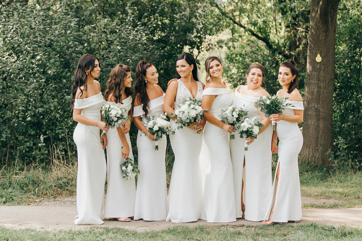Bride posing with her bridesmaids who are wearing matching white dresses