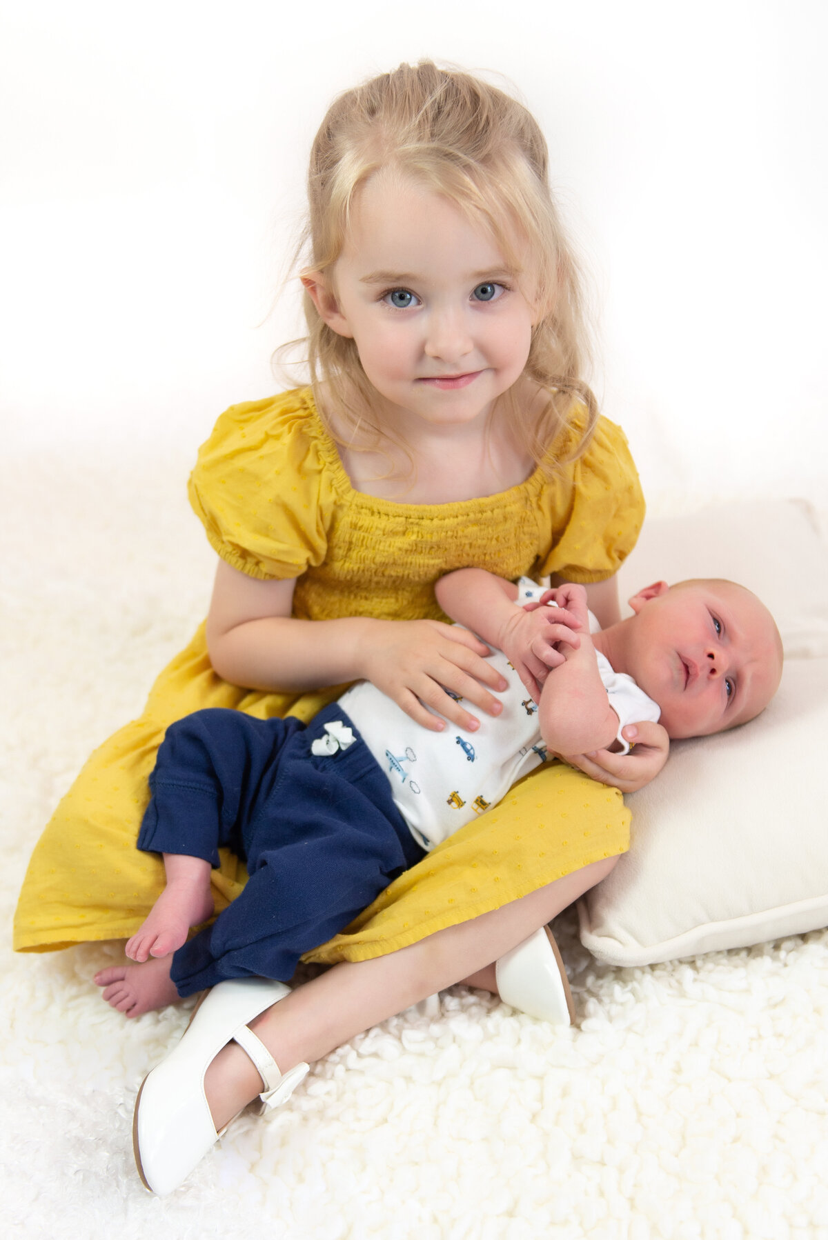 Newborn baby boy being held by his big sister