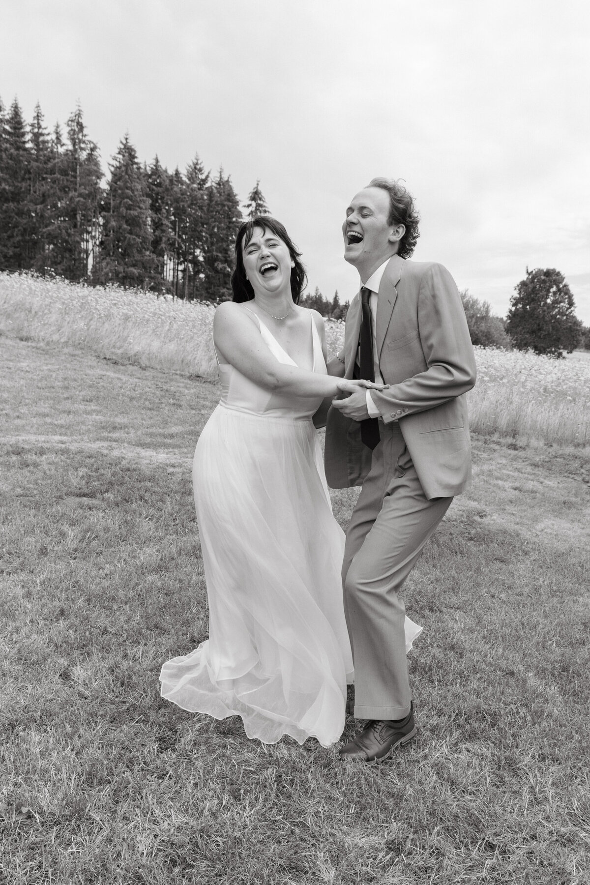black and white portrait of couple laughing and holding hands on their wedding day