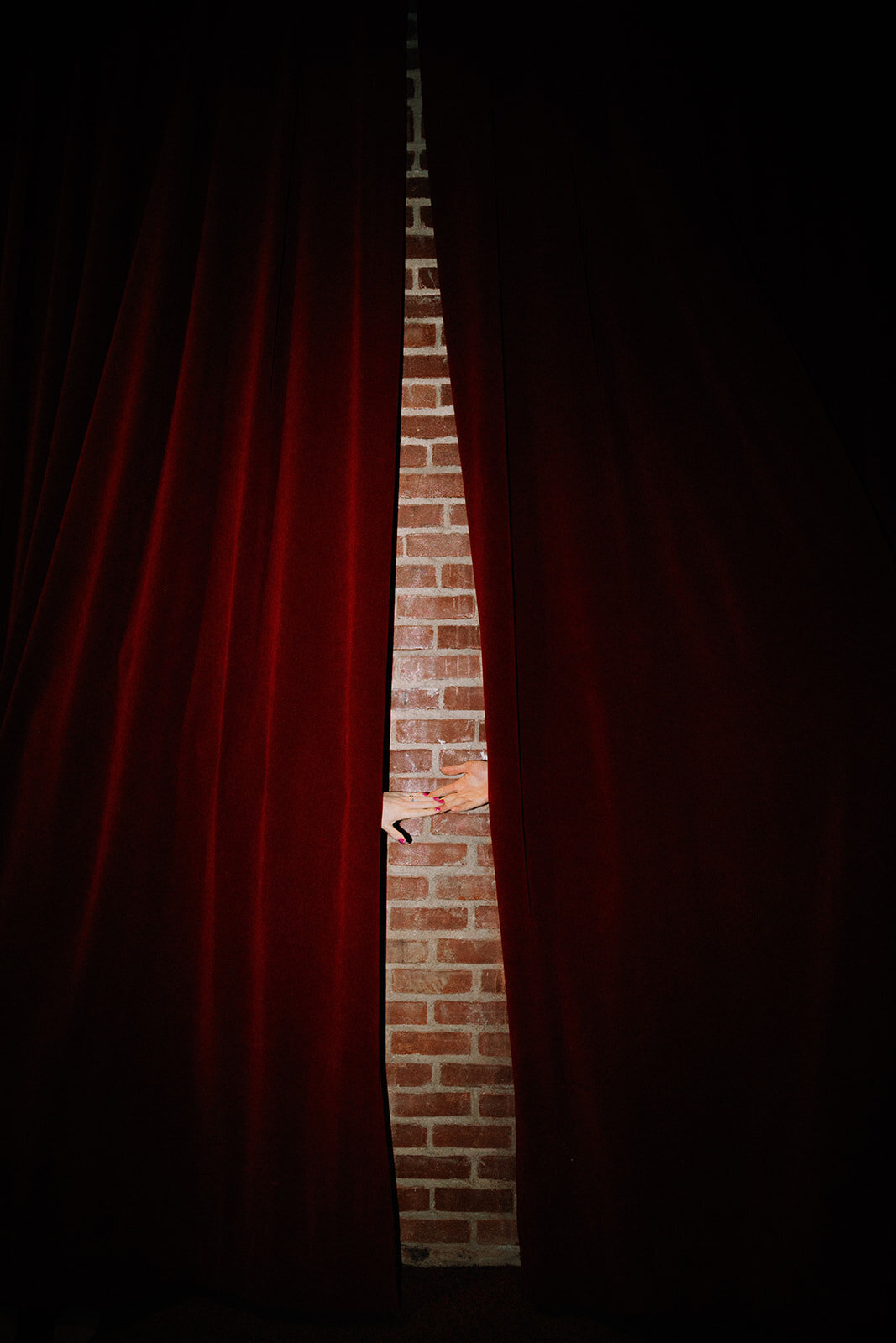 A couple holds hands behind a red curtain at the Met in Philadelphia