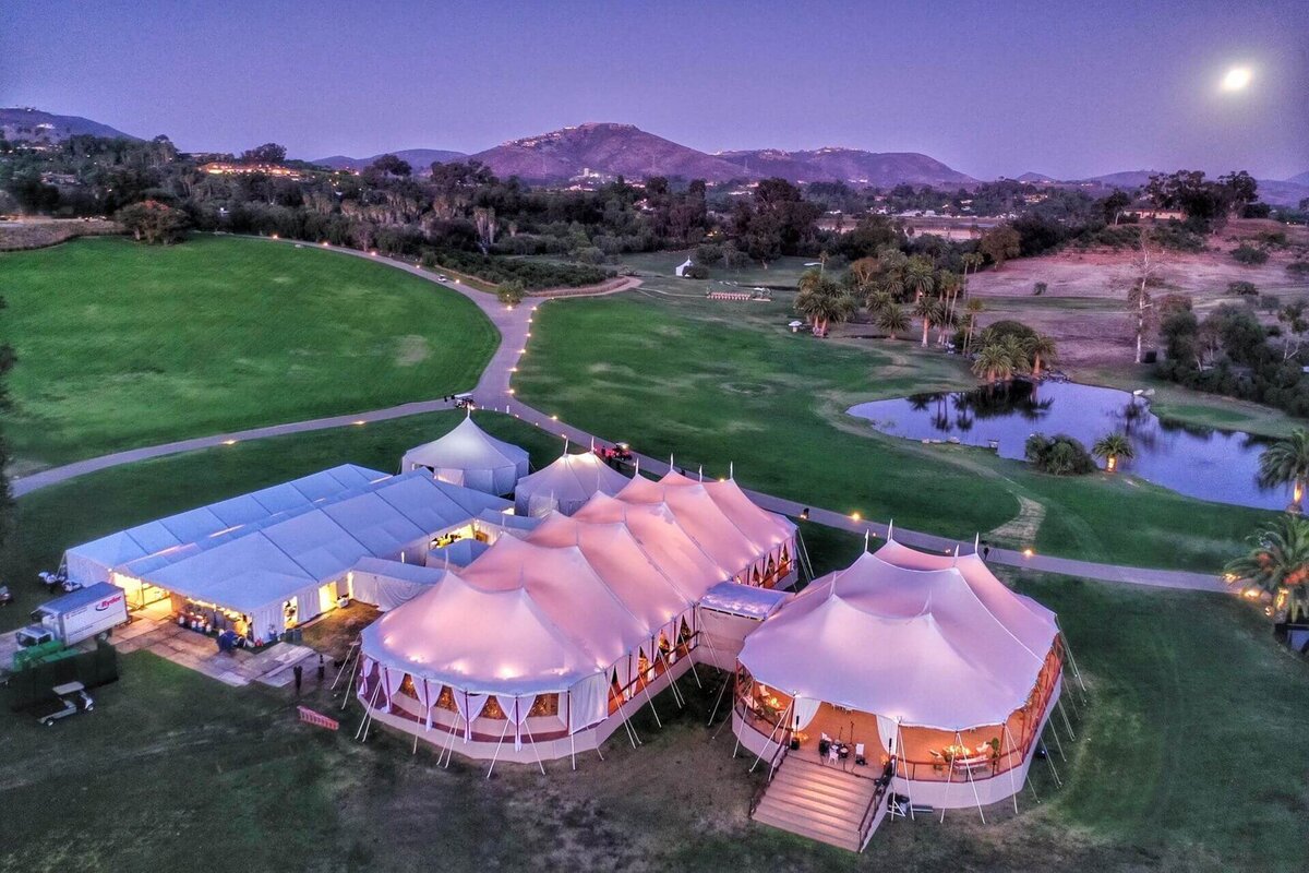 Three marquees set on a large golf course. Tw oof the marquees are pole marquees and one is a frame marquee and they are all connected.