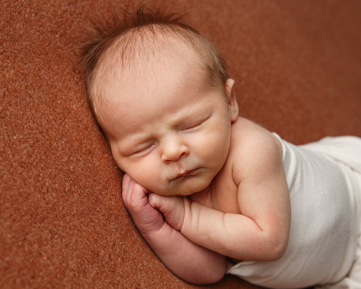 Close up portrait of a baby sleeping on his side with his little hands under his cheek