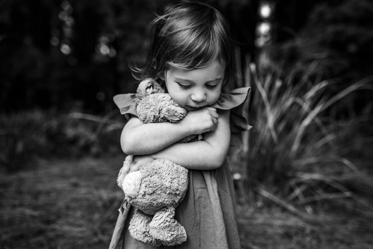 3-year-old girl hugging favorite stuffed animal close at Berkeley garden