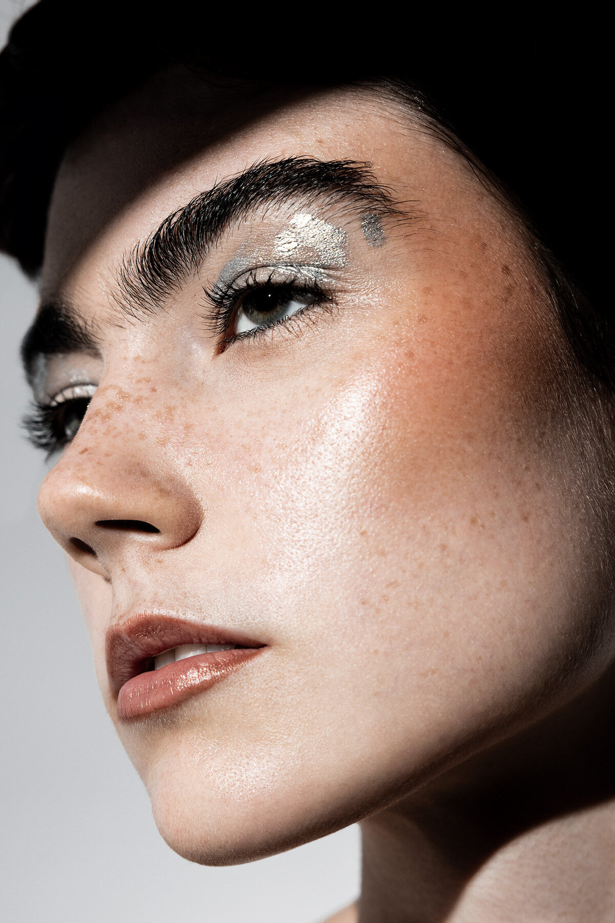 Beauty photography portrait of freckled model with silver metallic eyeshadow 