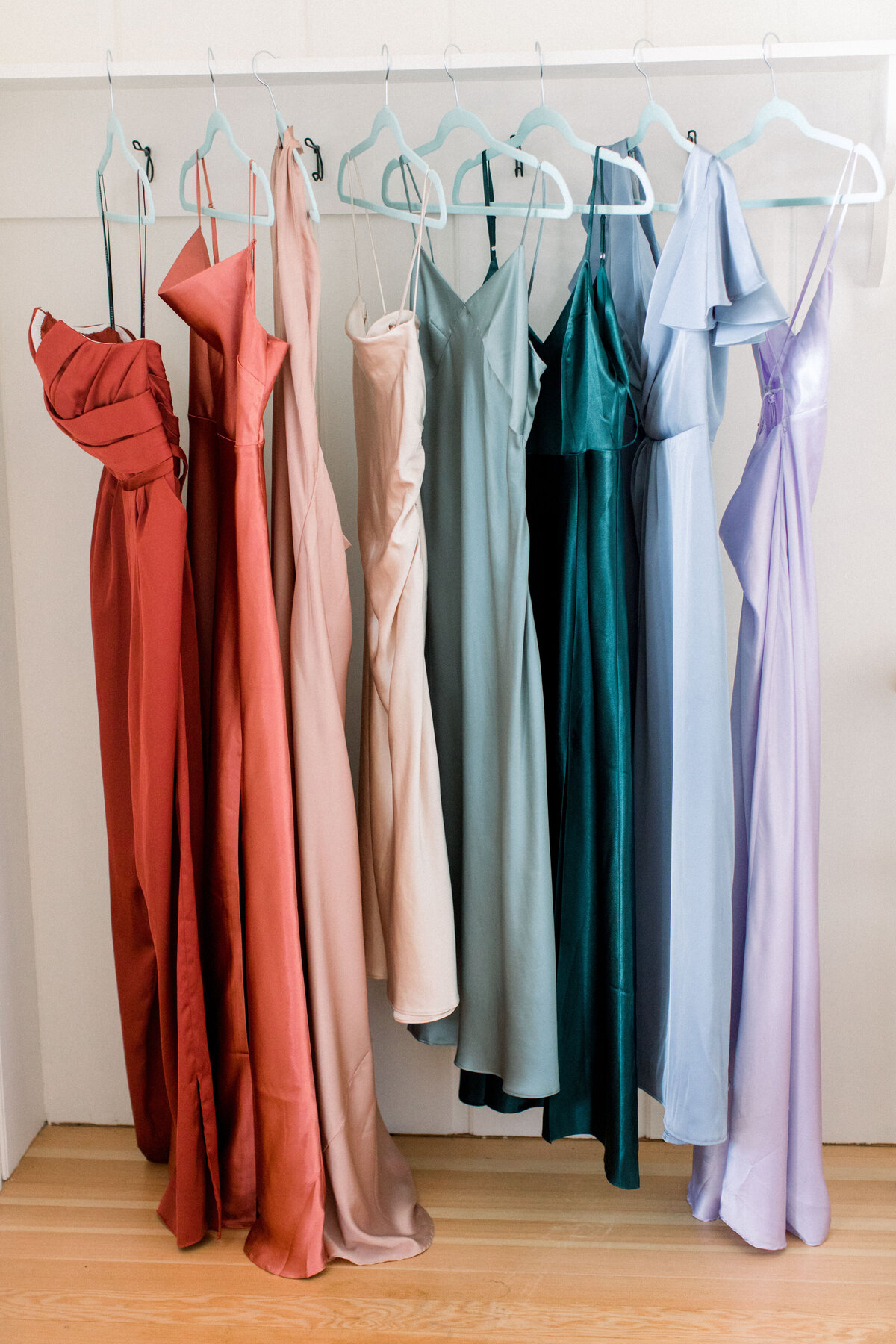 Different colored bridesmaid dresses hanging on a rack