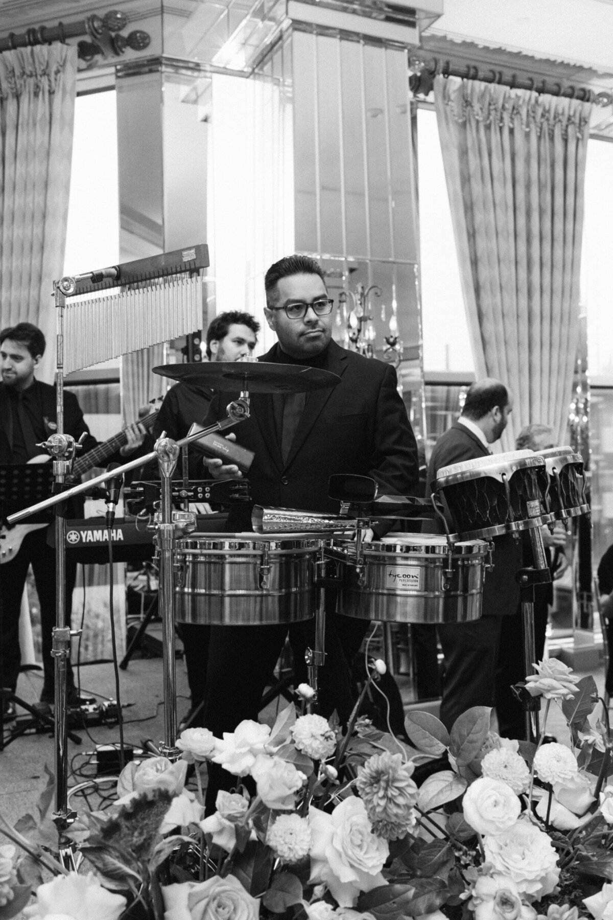 A black and white wedding photo of the drummer of the band during the wedding reception