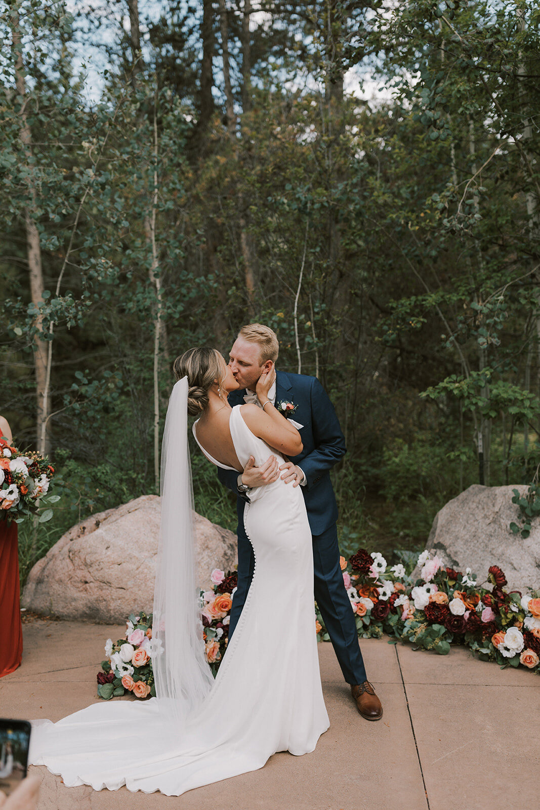 Bride and groom kissing each other and a colorful florals behind