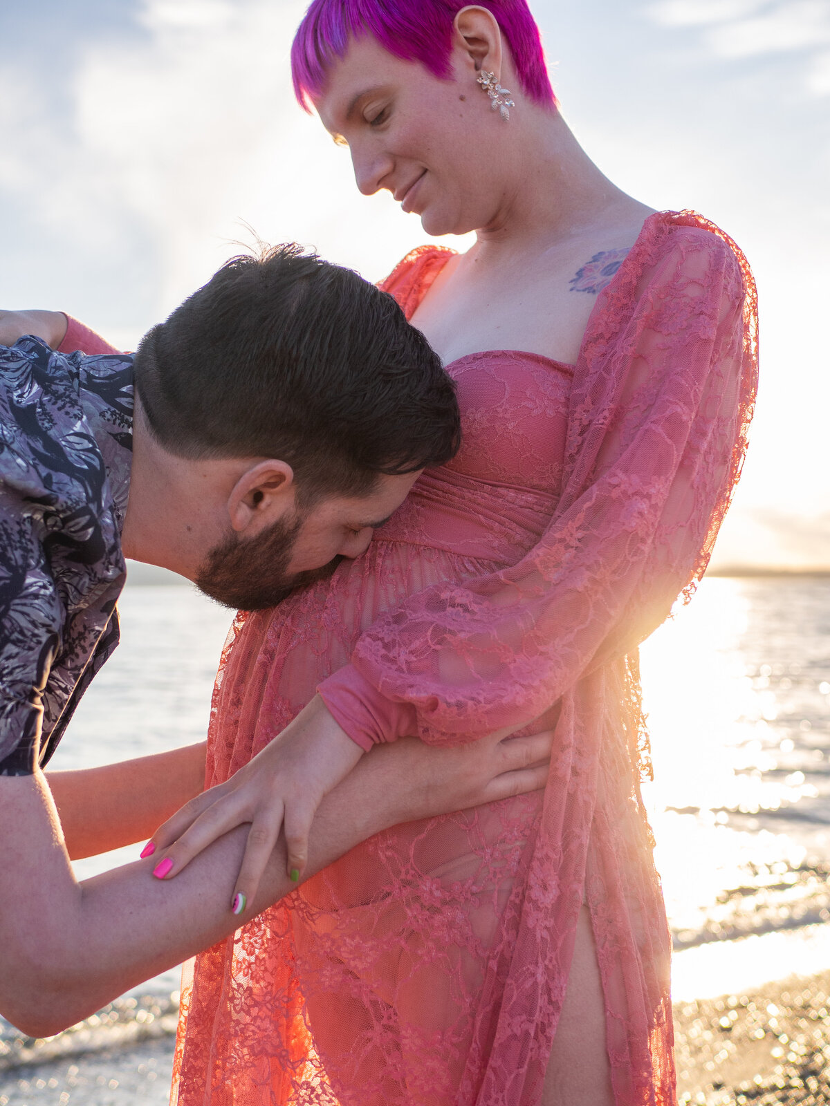 a husband kisses his wife's pregnant belly at Edmonds Beach, WA.