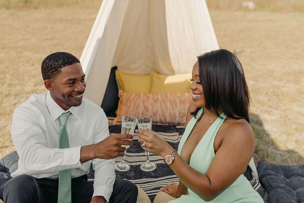 How to propose in Austin couple smiling while clinking glasses of champagne