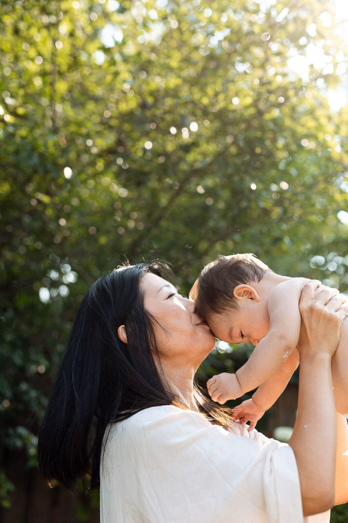 Mom kissing baby on head after cake smash in Cleveland Heights.