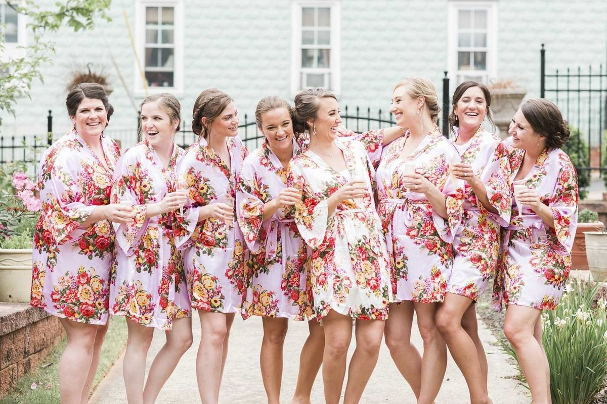 Bride and bridesmaids laughing in their robes drinking champagne