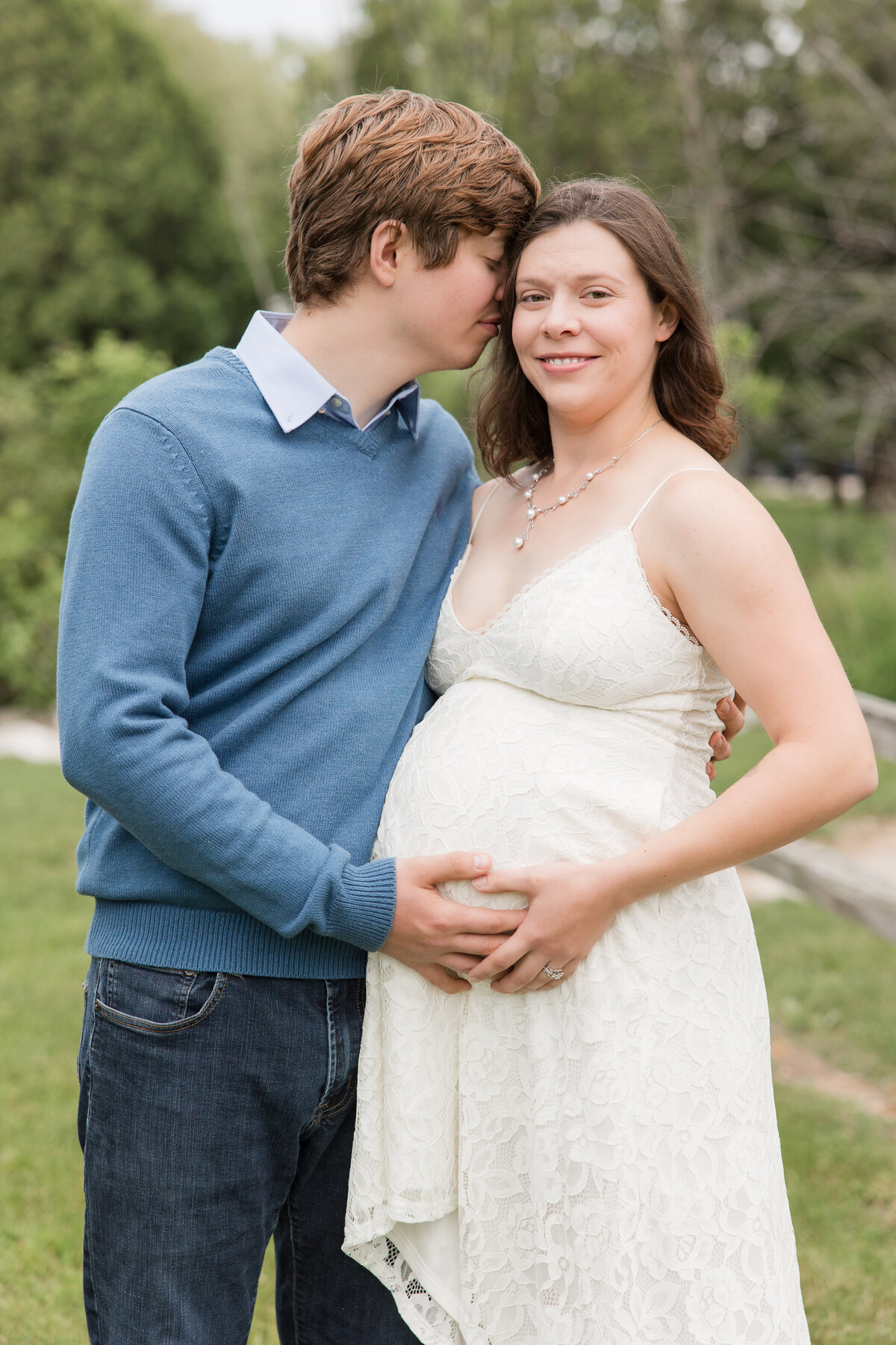Expectant couple holding mama's baby bump while mother is smiling at the camera