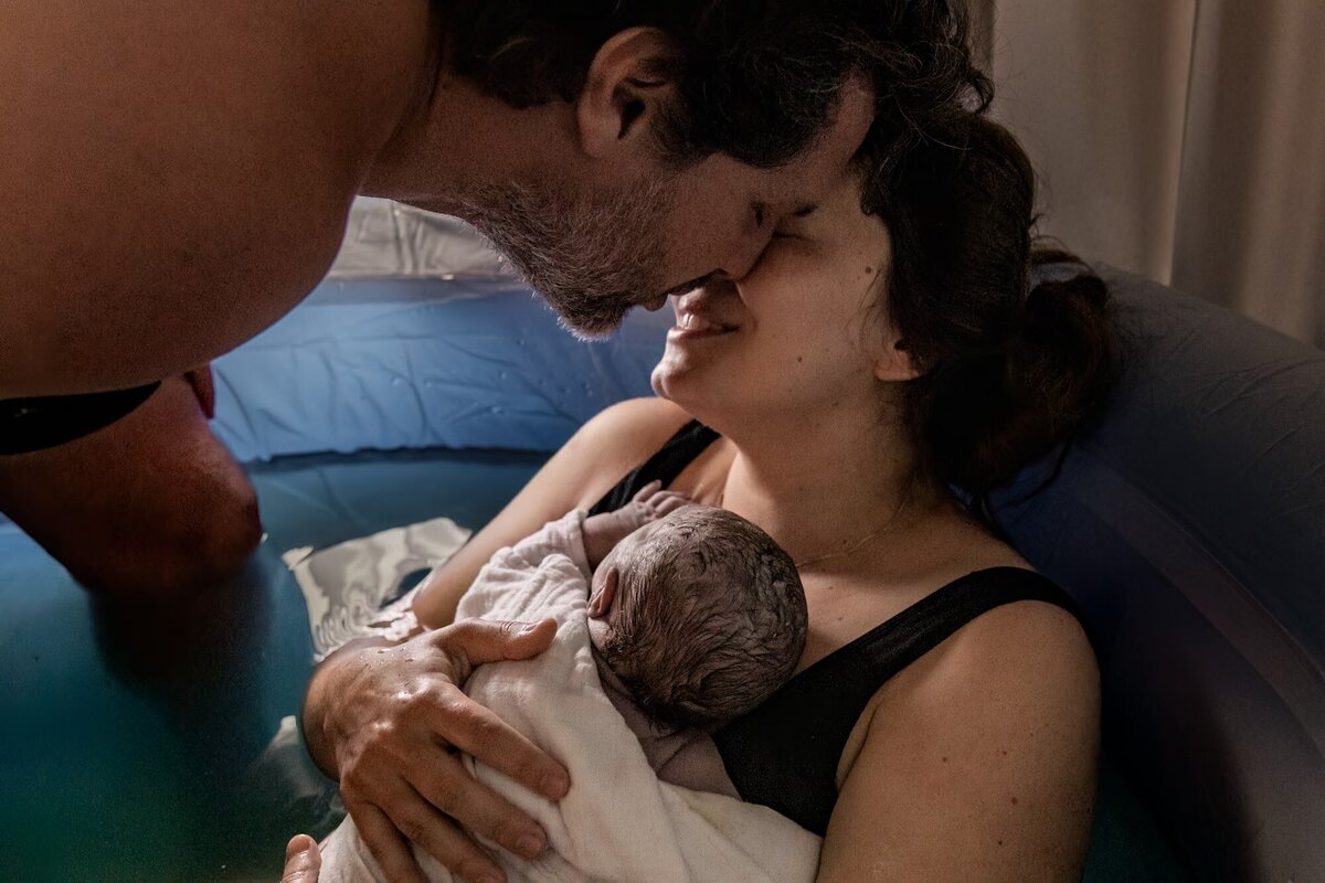 Een geboortefotograaf houdt een pasgeboren baby vast.