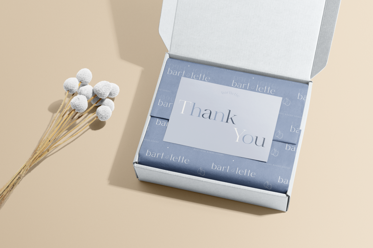 Open cardboard box with branded wrapped tissue paper and thank you note inside