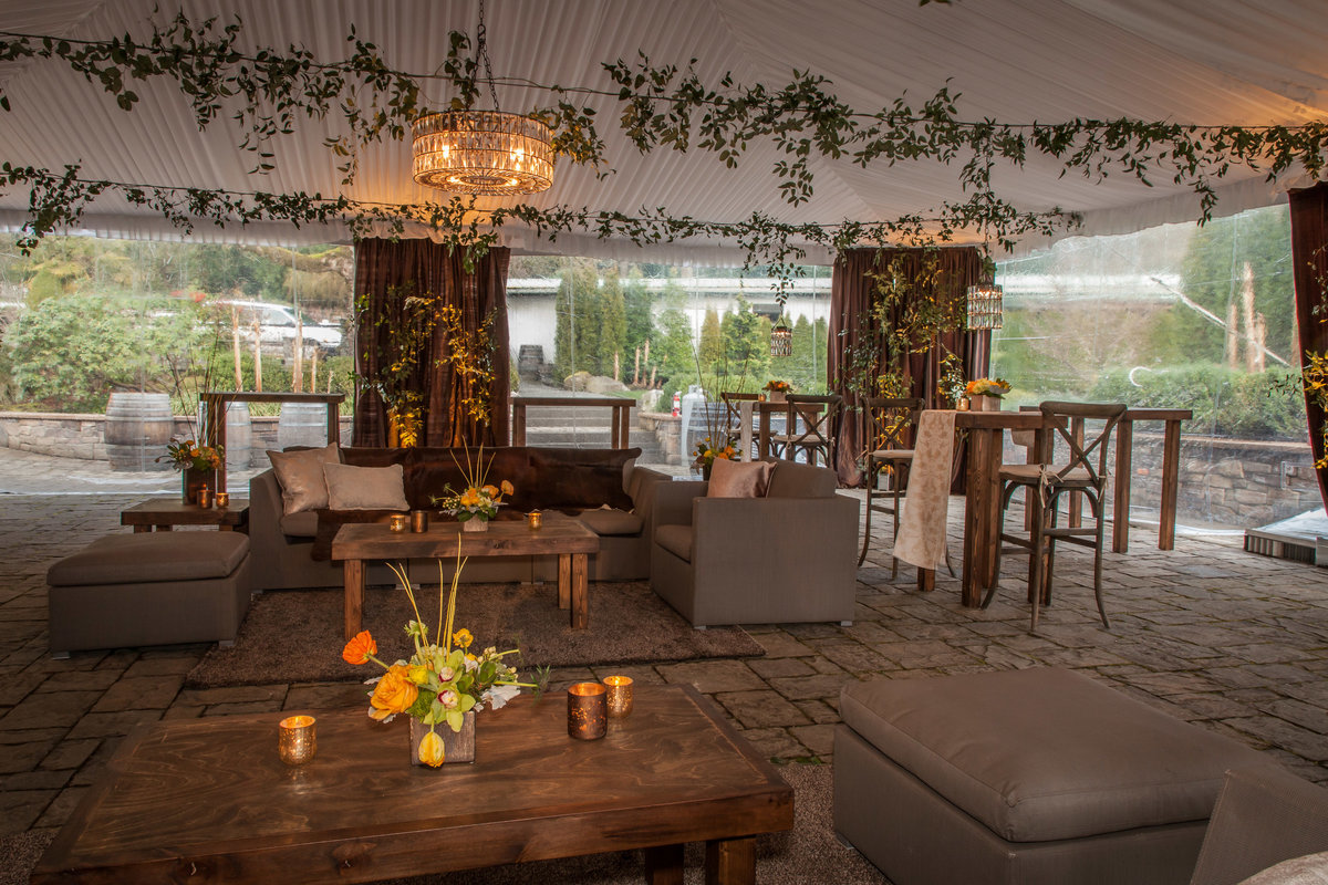 corporate party at Chateau Lill tent with ceiling greenery, lounge furniture, and yellow flowers, and brown draping