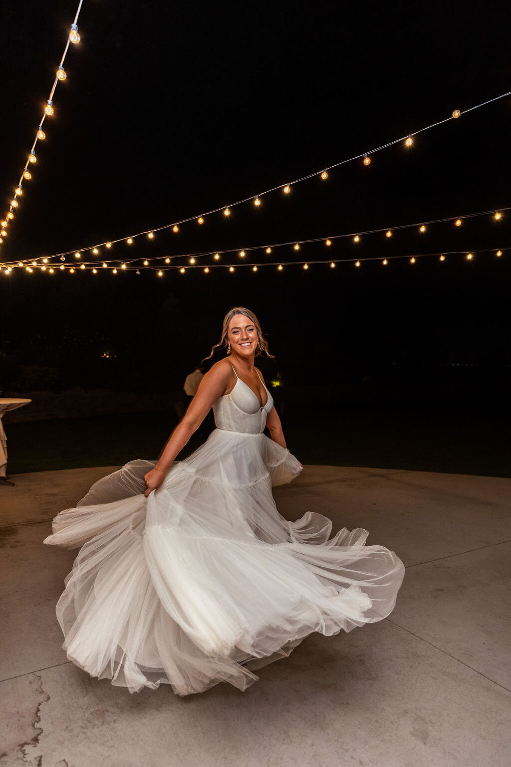 Bride spins under the twinkle lights during her wedding reception at Bonnie Blues Event Venue.