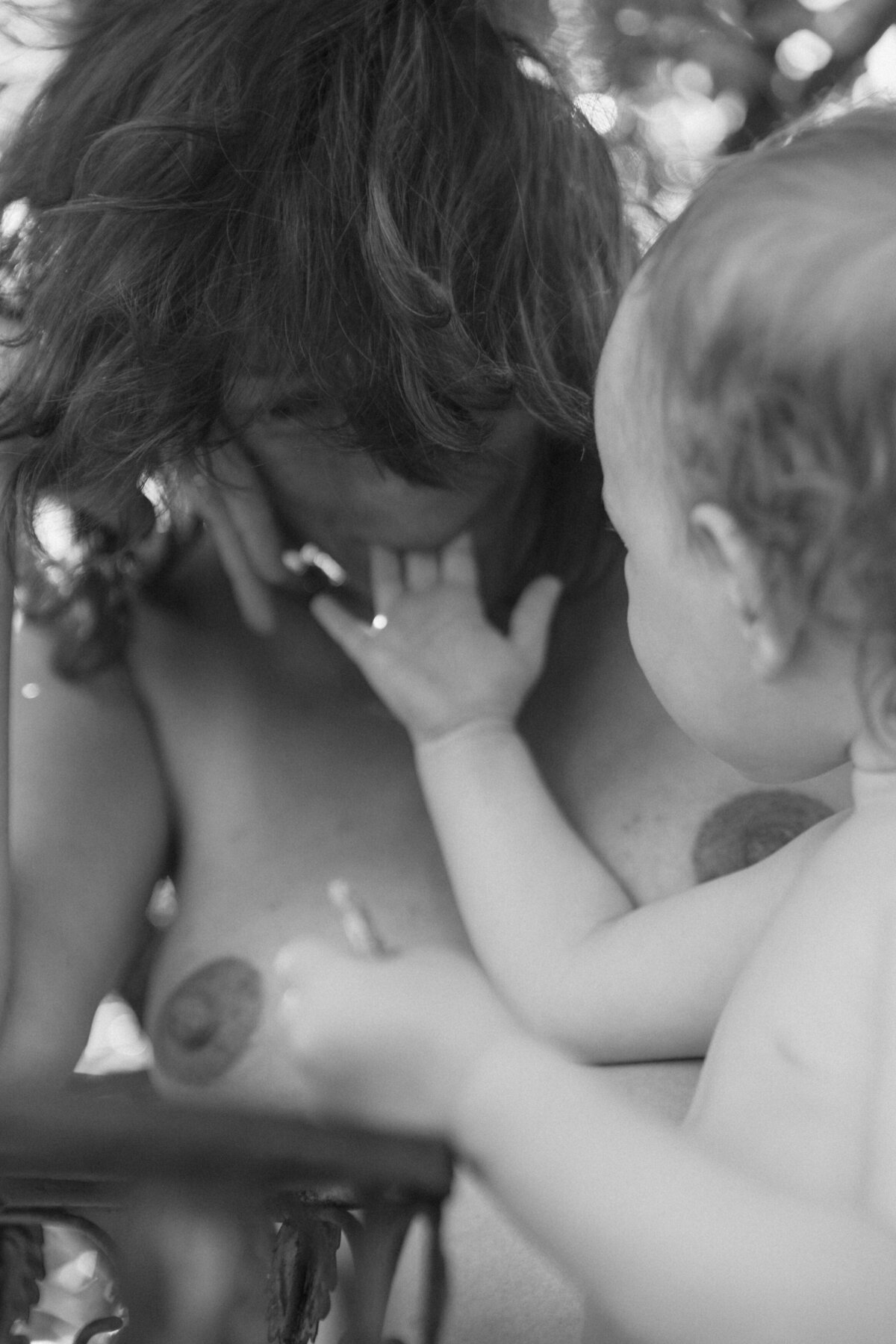 Black and white image of toddler daughter offering her mother a taste of food while mother smiles