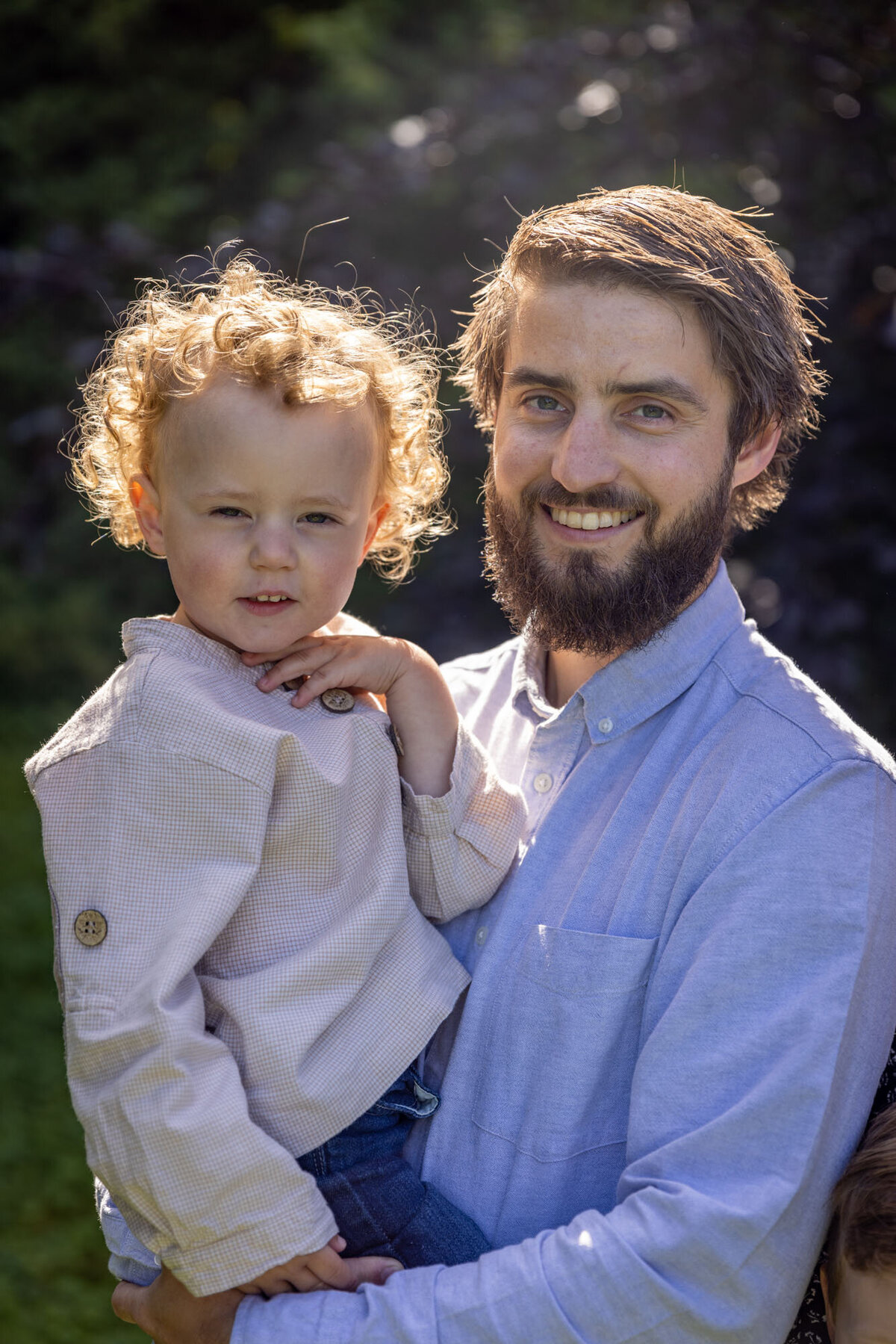 Familiefoto av far og sønn; far holder sønn på hoften sin.
