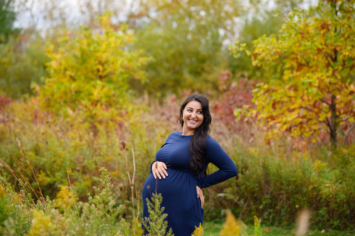 pregnant woman wearing a blue maternity dress for her Burlington, ON fall outdoor maternity photography session