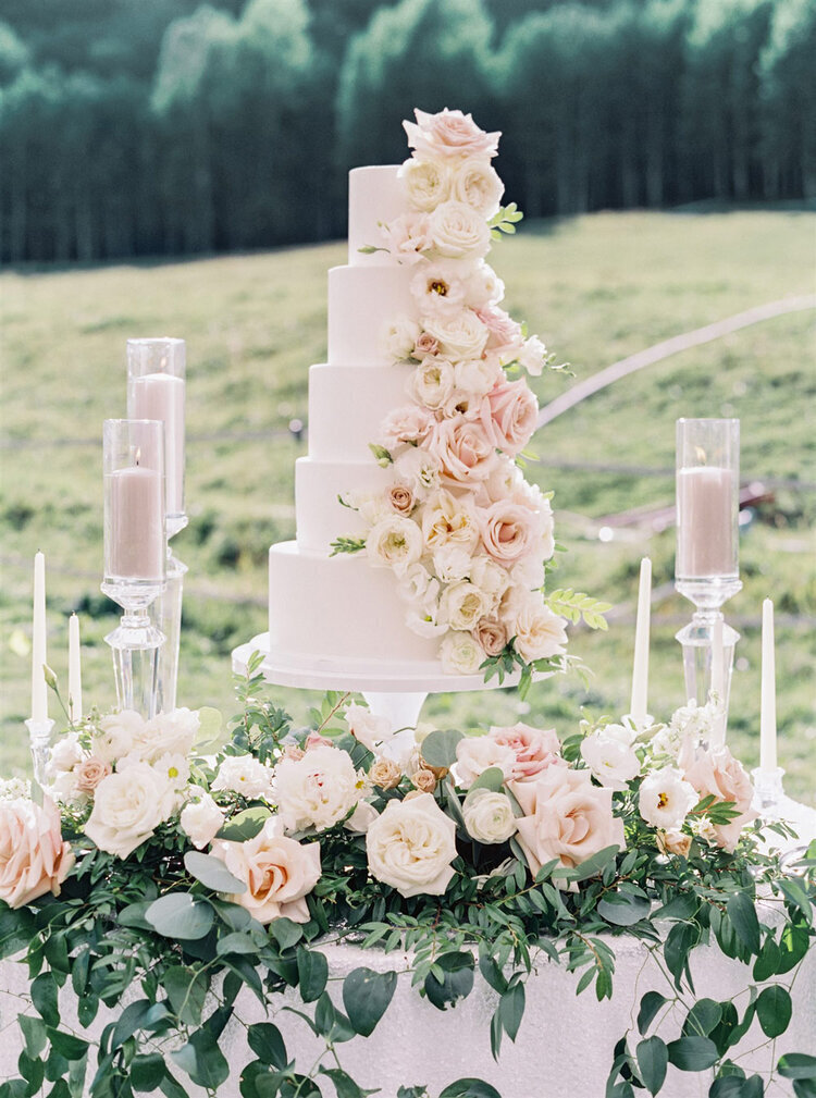 Custom tiered wedding cake with floral accents and decor at an outdoor wedding in Colorado
