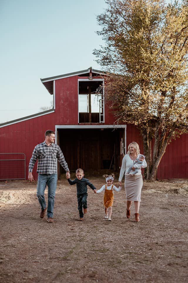 Family walking by barn for family photoshoot in Prescott Arizona
