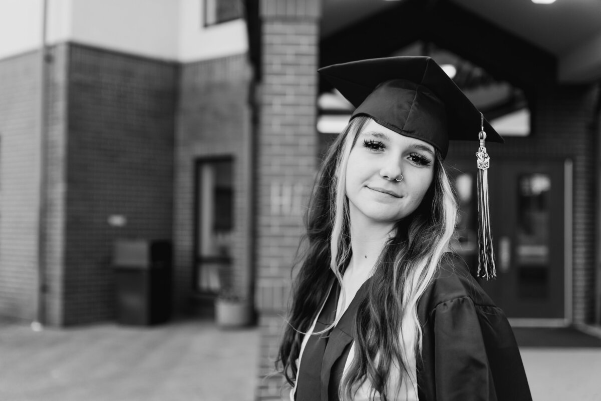 High school senior in black and white photos wearing cap and gown for senior portraits