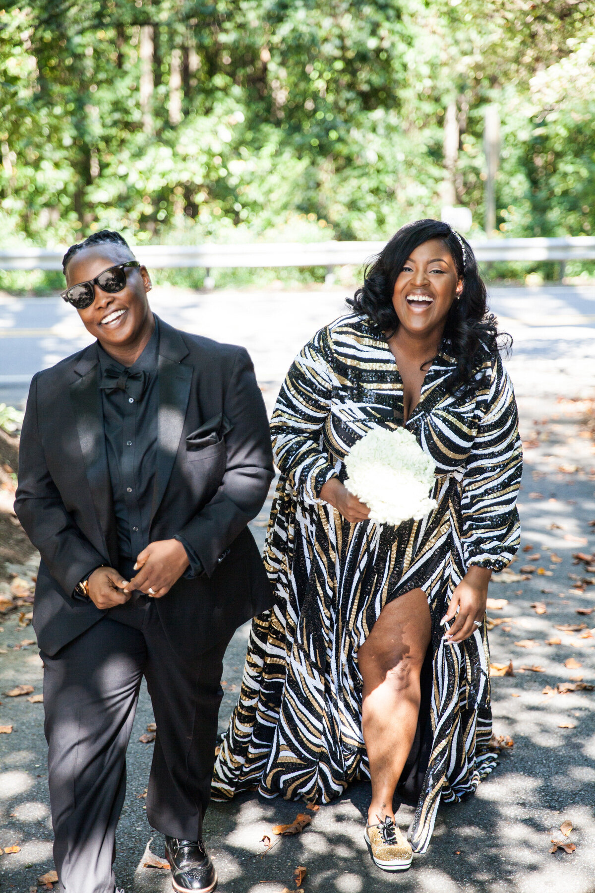 A newlywed couple walking along a road together laughing 