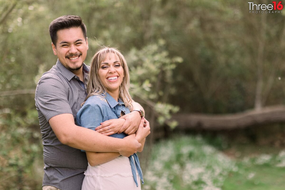 Engaged couple share big smiles for the photographer