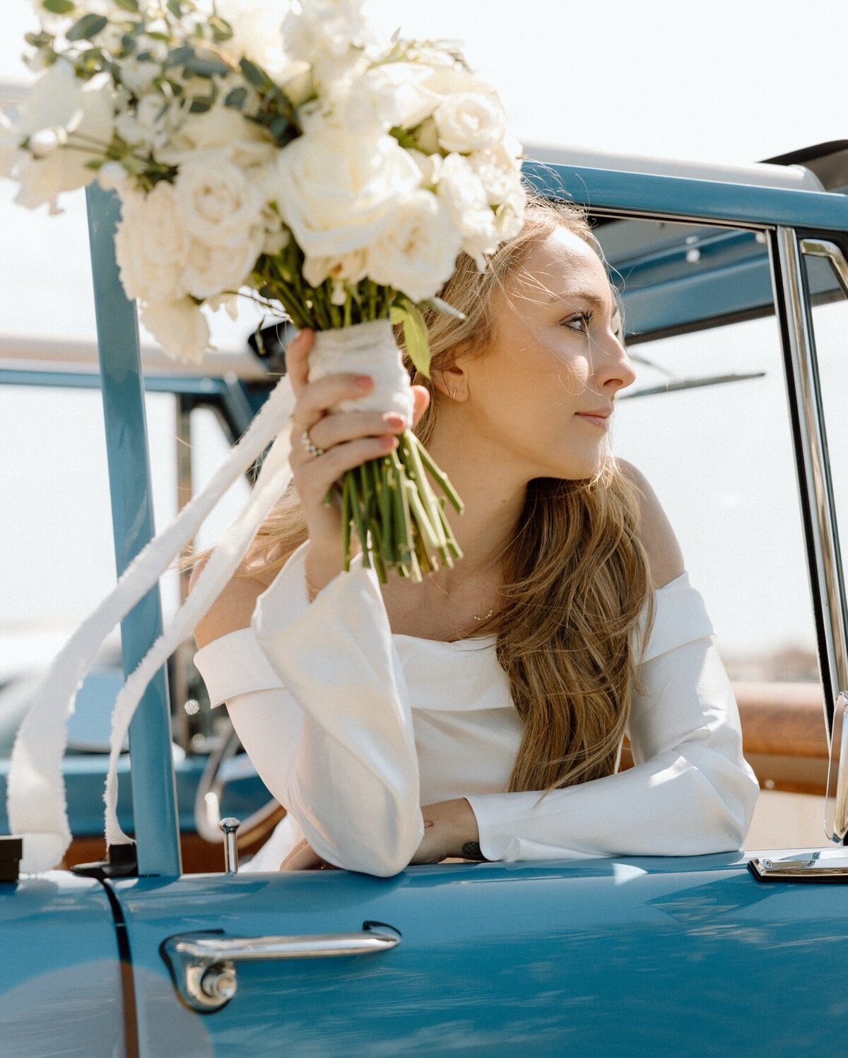 Bride holding bouquet in vintage blue bronco during a Charleston elopement at folly beach.