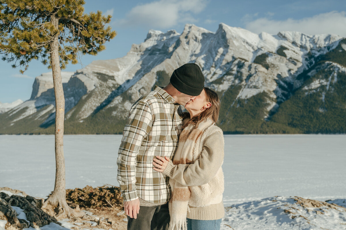 Newly engaged couple go in for a kiss at Lake Minnewanka.