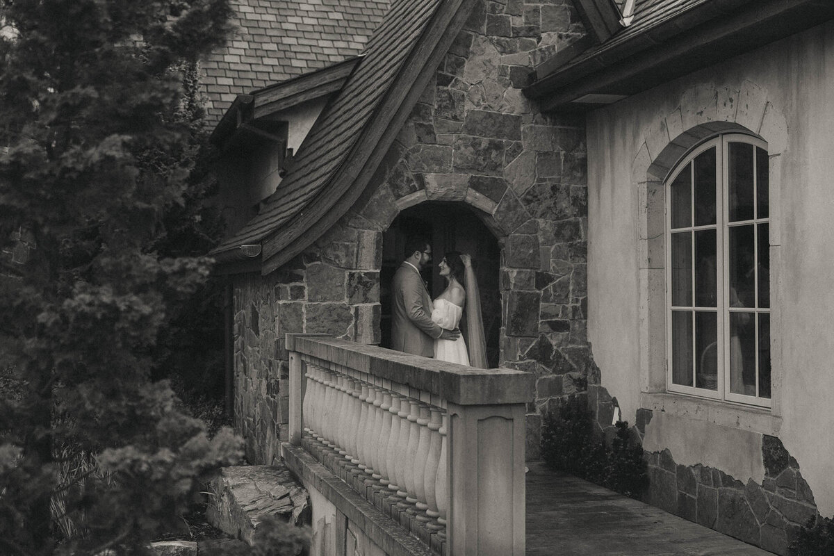 Bride and groom embrace standing on the balcony at the Chateau wedding venue.