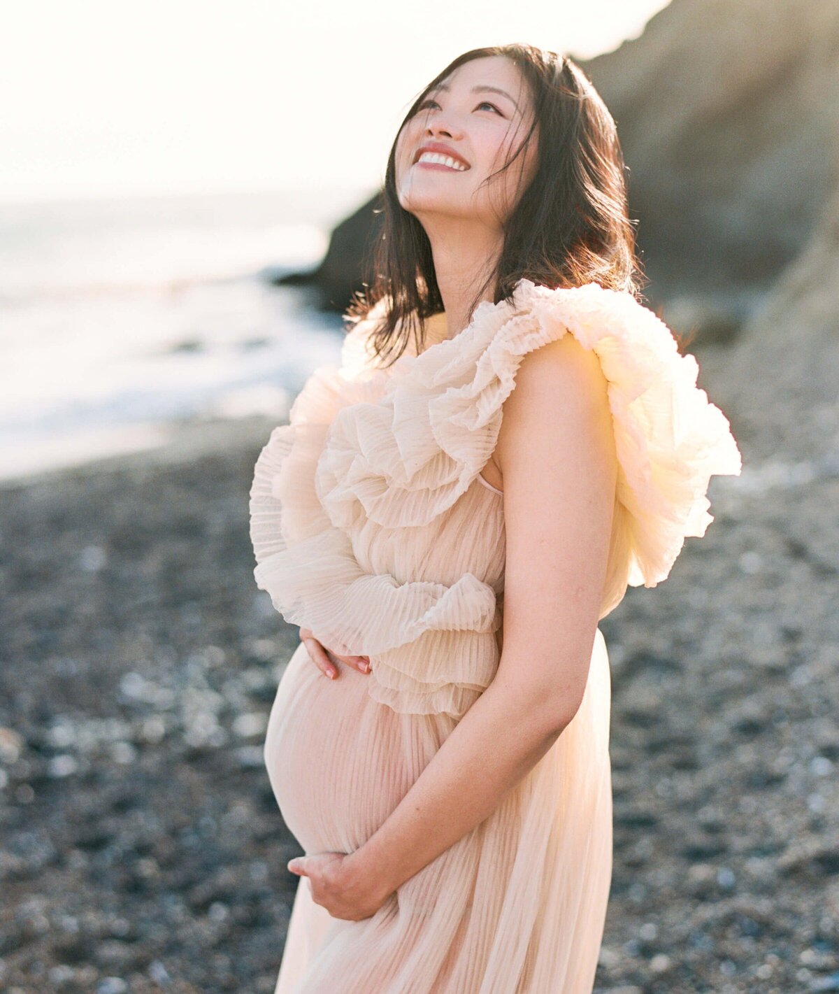 maternity photography in san francisco bay area beach with pregnant woman holding her belly