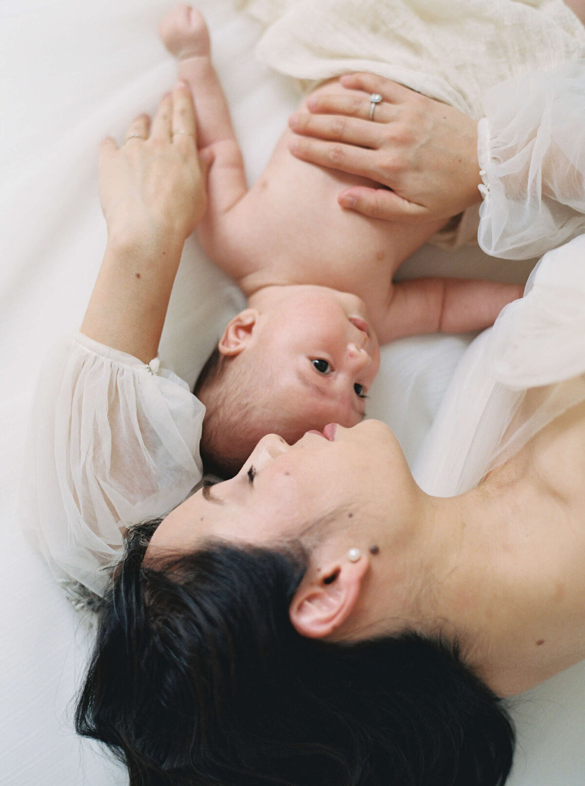 Mother laying on bed for newborn photos with Bay Area newborn photographer session.