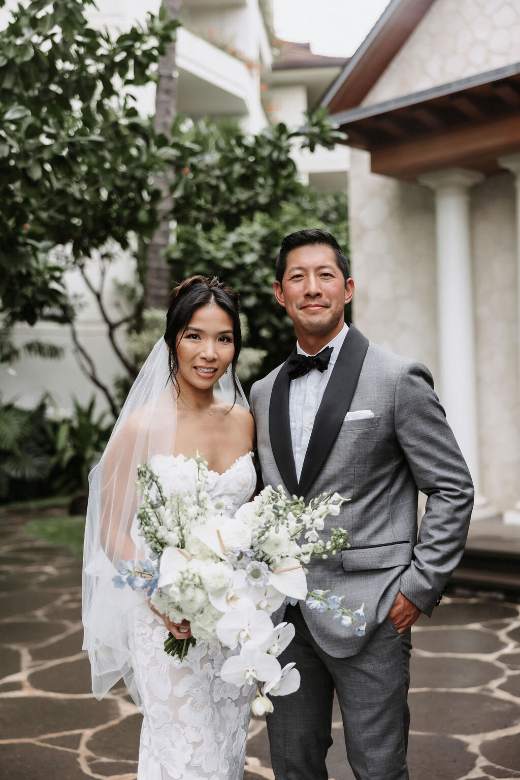 bride and groom posing in front of white chapel at four seasons oahu