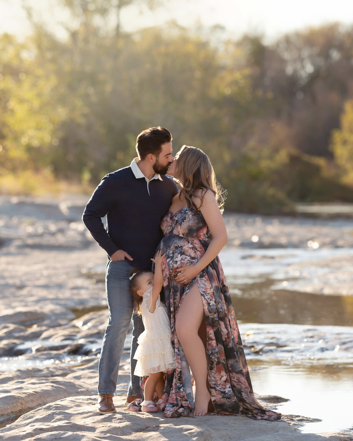 Unique maternity photography of expecting couple standing in shallow stream during outdoor session