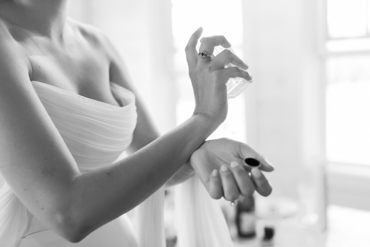 bride applies perfume on wedding day