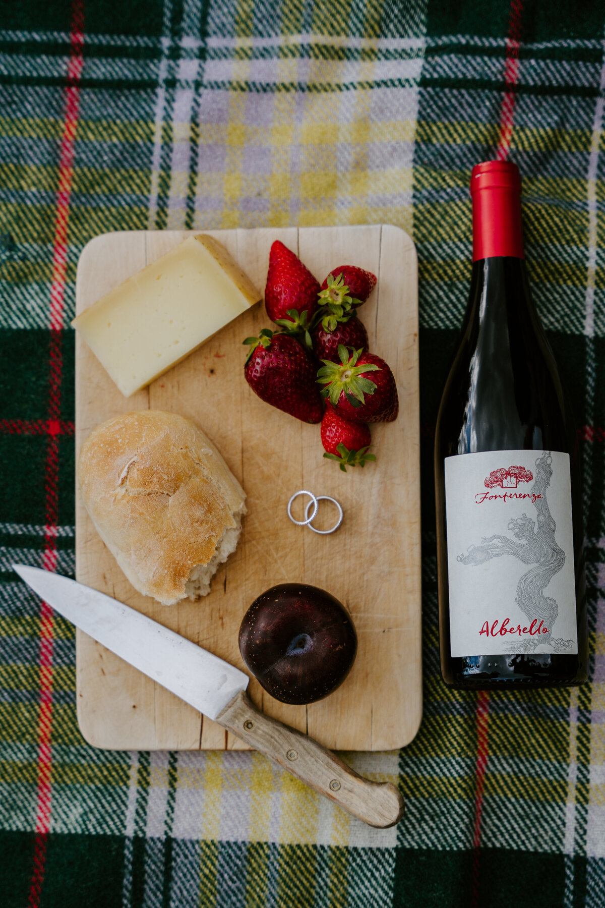 Picnic spread with wine, bread, cheese, and strawberries.