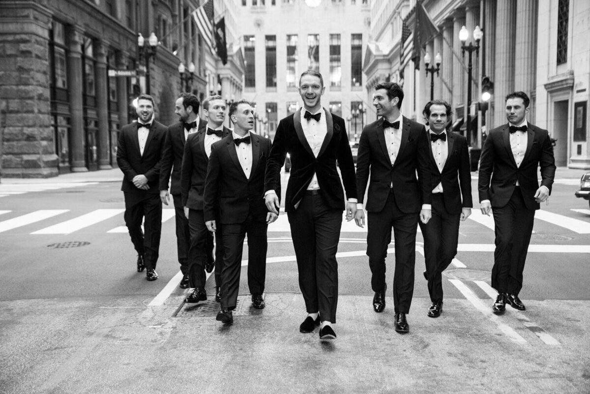 A group of men in tuxedos are walking down a street