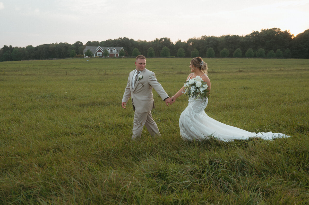 couple running in field during wedding photos