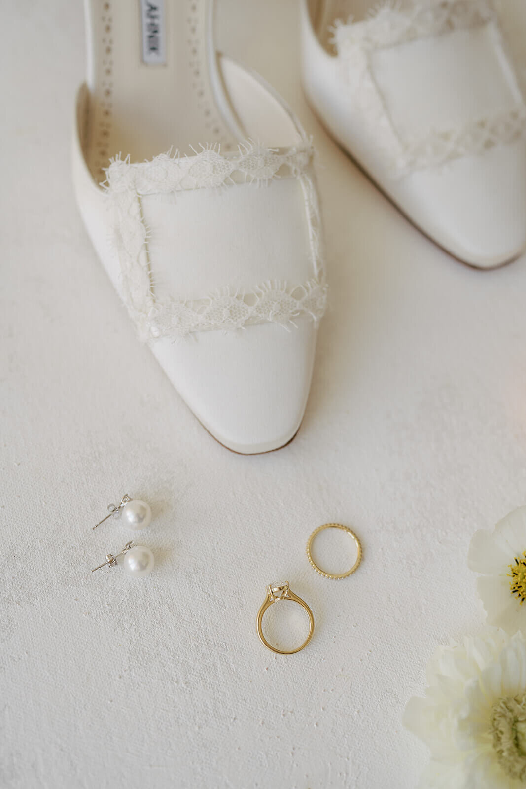 A close up of bridal details featuring pearl earrings, bridal wedding rings, and bridal shoes for the Aspen Meadows Resort wedding.
