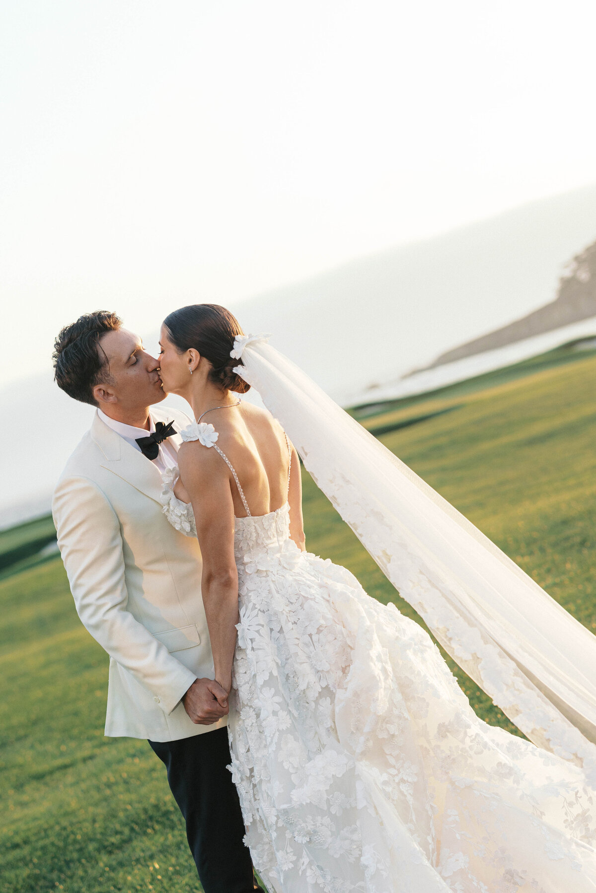 Bride and groom kissing on Pebble Beach Golf Course